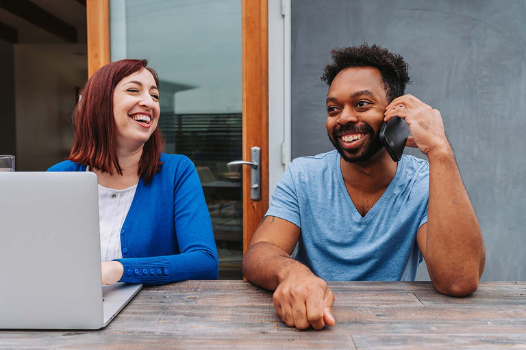 Coworkers laughing while working together at an outdoor table