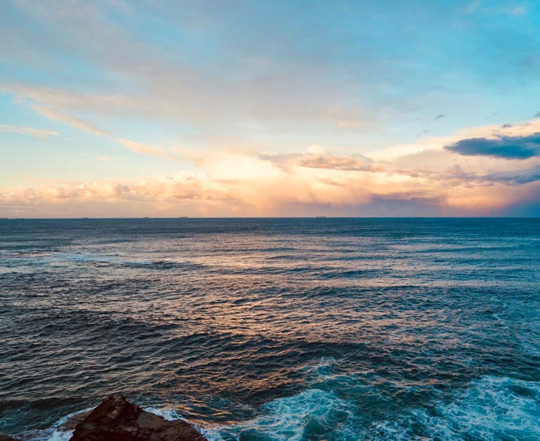 Calm ocean waves with cloudy sky just before sunset