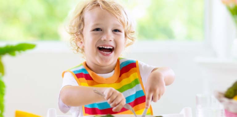 A boy child posing to eat with spoon and fork on hand