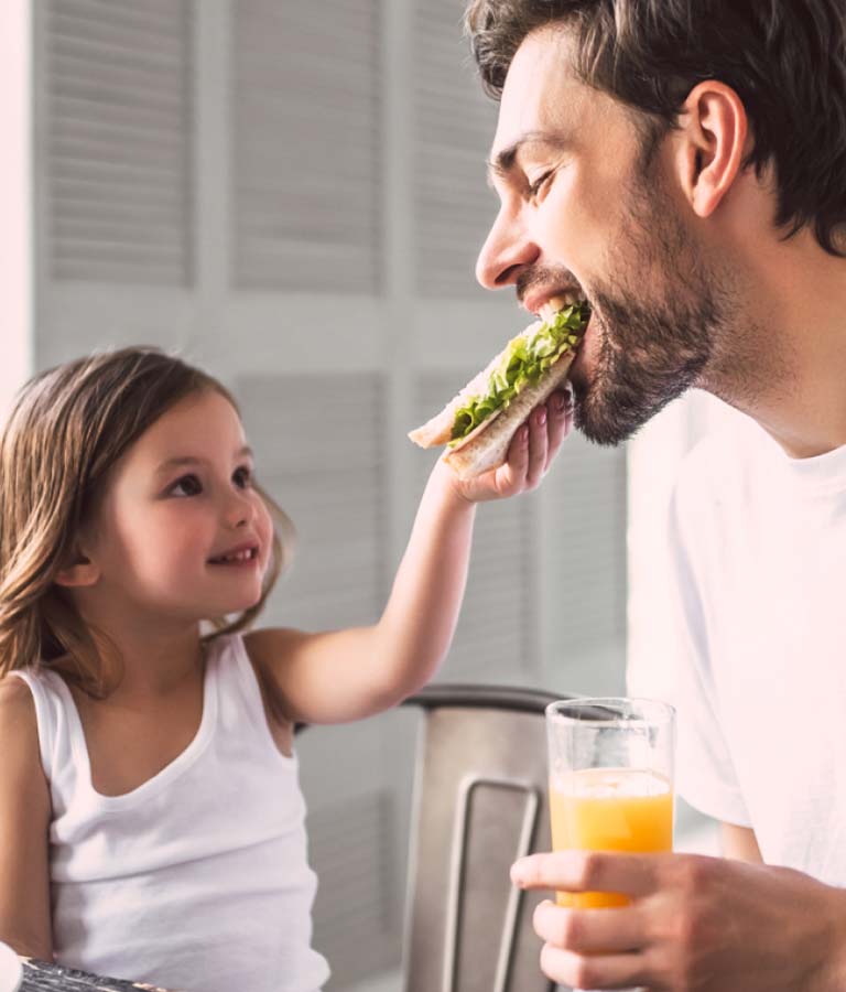 Little girl feeding his daddy a sandwich